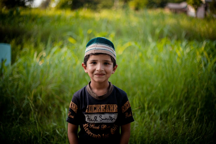 a young boy standing in a field of tall grass